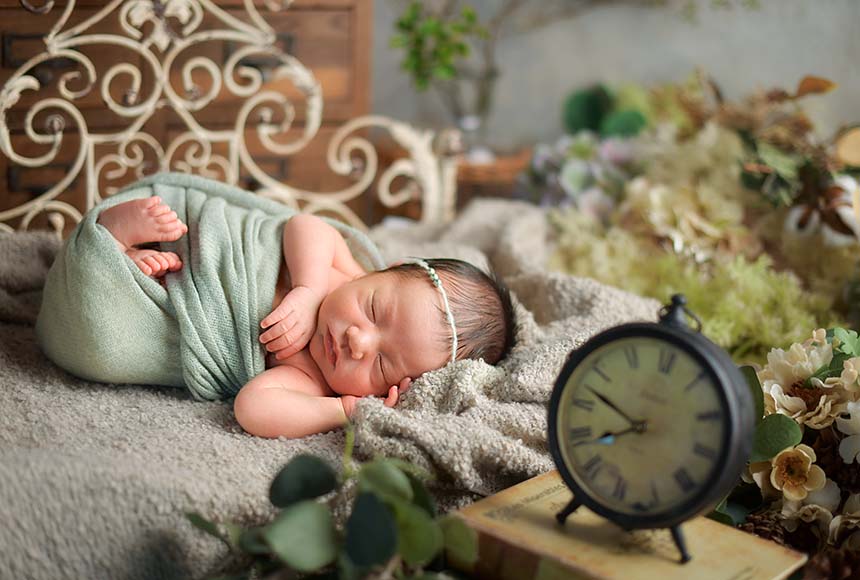 ブルーのおくるみに包まれて眠る新生児の男の子