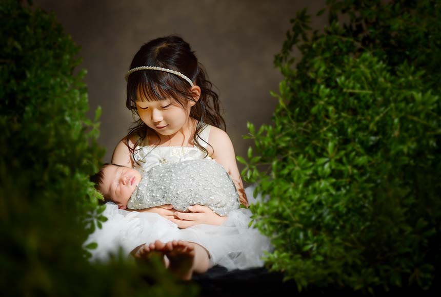 お姉ちゃんが新生児の妹を抱くニューボーンフォト