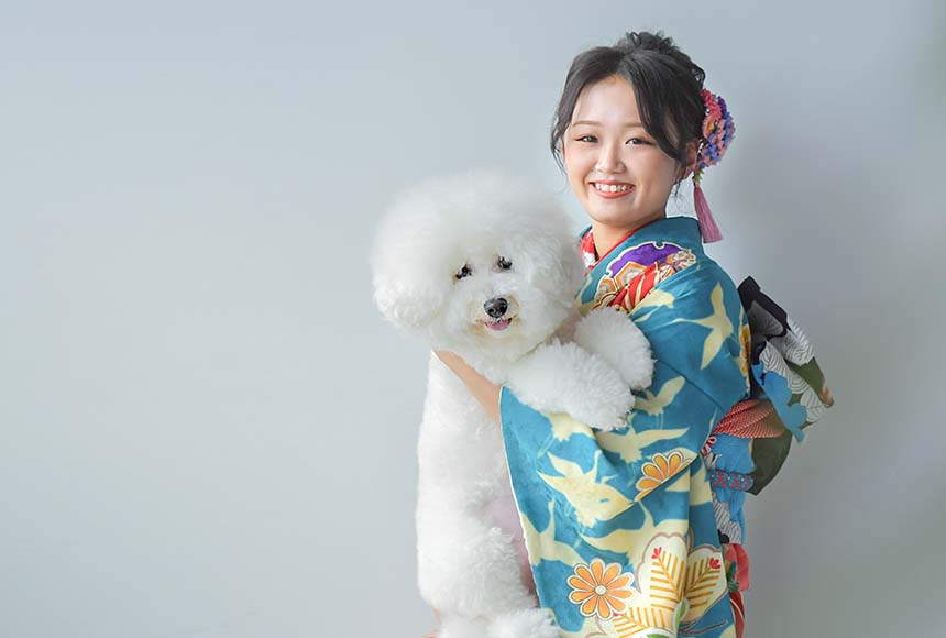 白いワンちゃんを抱っこする青の振袖を着た女の子