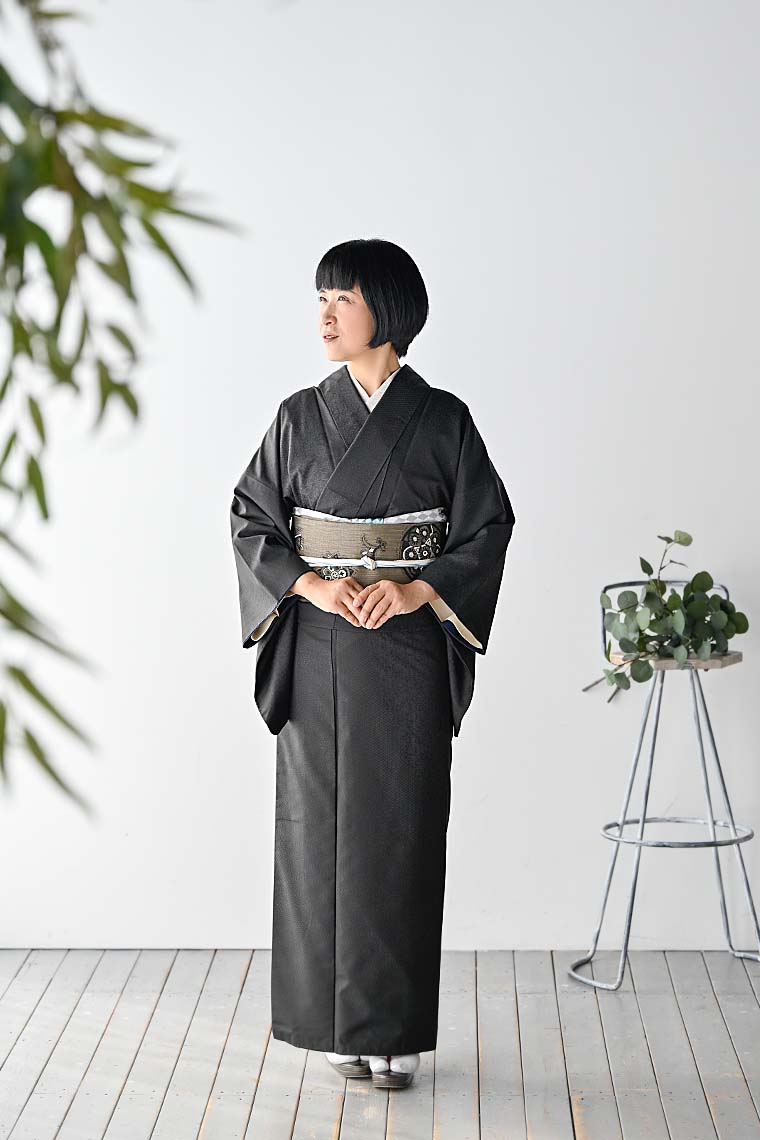 黒色の着物を着て立つ女性