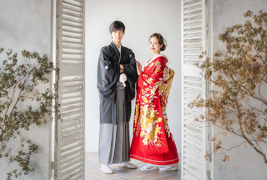 赤い友禅の着物を着た新婦と紋付袴の新郎