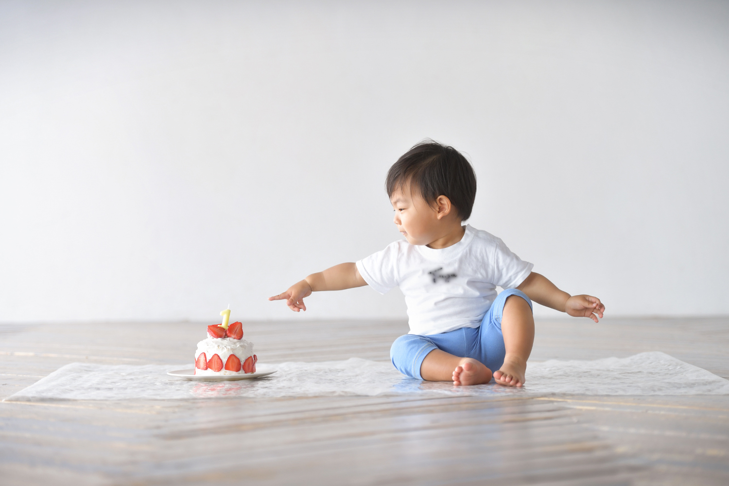 手作りのスマッシュケーキに手を伸ばす1歳の男の子