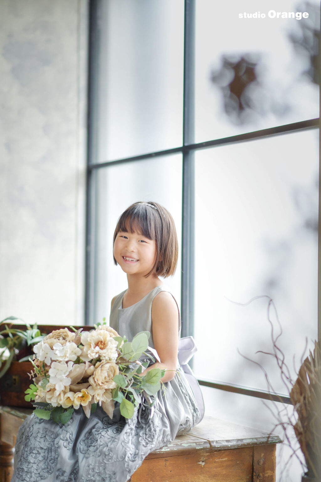 グレーのドレスを着た、ブーケを持つおかっぱ頭の女の子