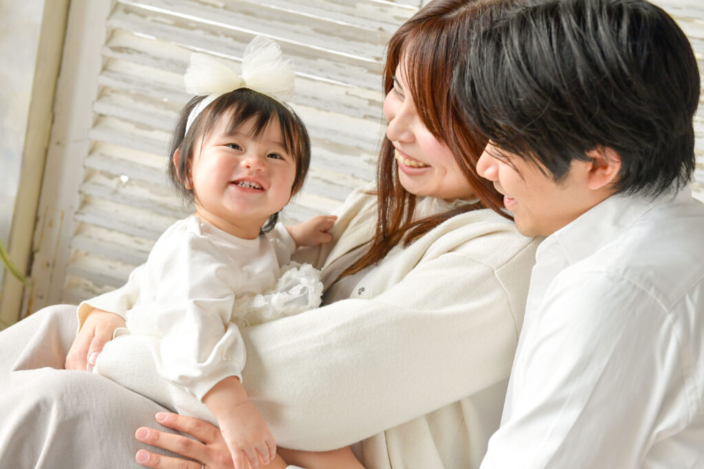 お母さんとお父さんが笑っている子供を見つめている写真