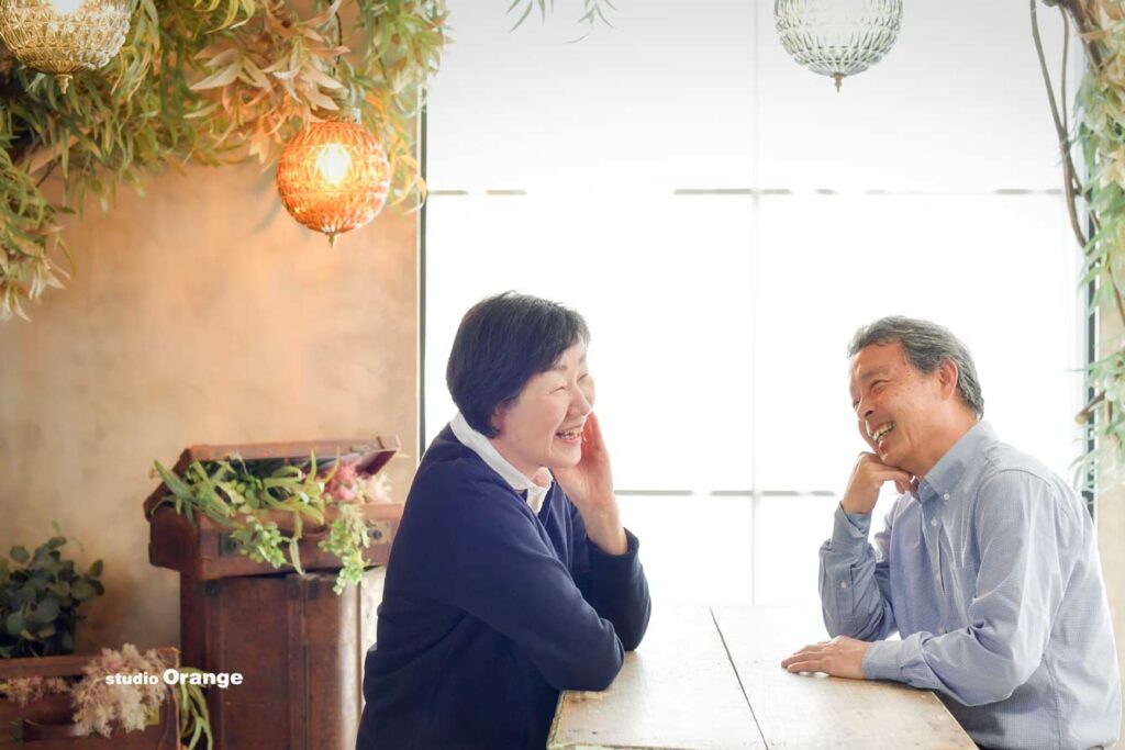 長年寄り添ったご夫婦が向かい合わせで笑っている写真