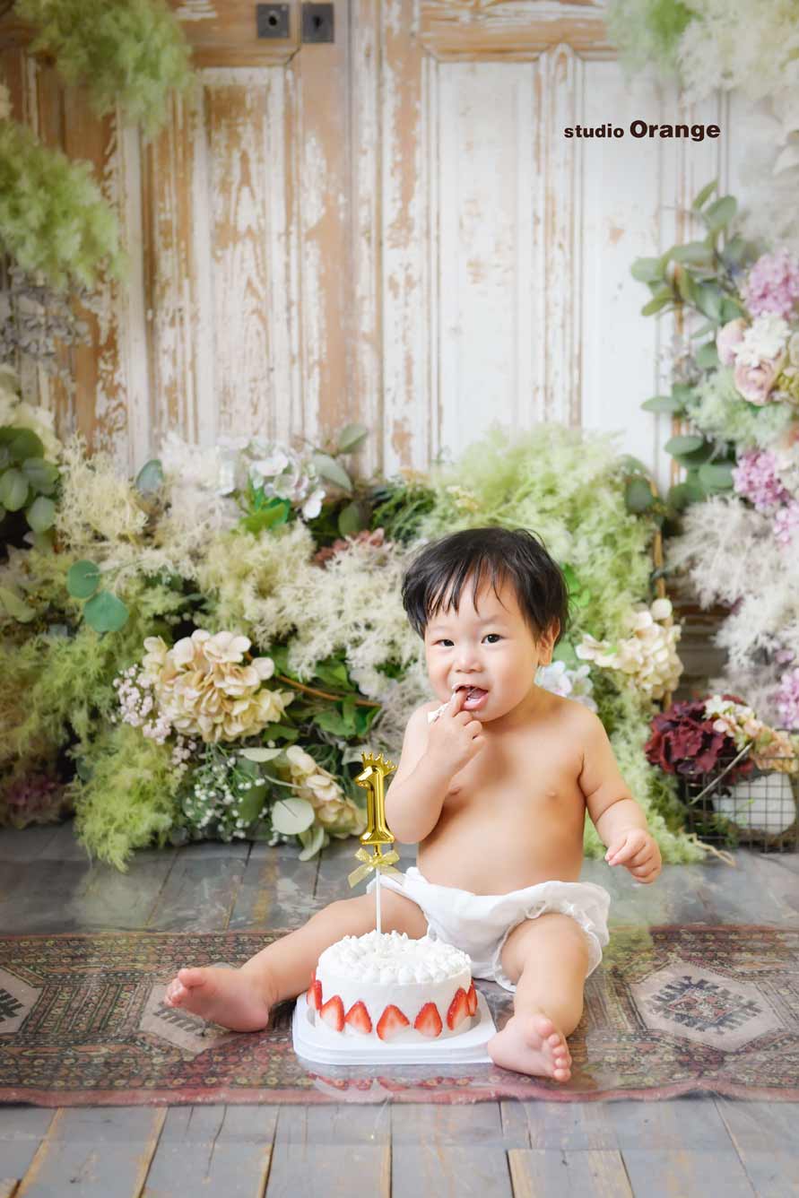 1歳お誕生日撮影スマッシュケーキでクリームがついた指を咥えている様子
