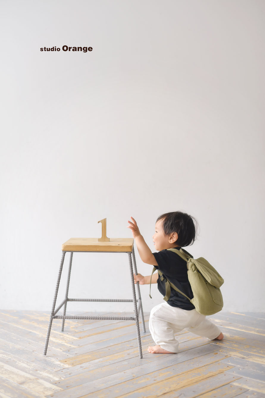 1歳お誕生日撮影台の上に乗っている1の木のブロックを取ろうと手を伸ばしている様子
