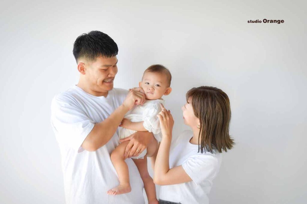 1歳女の子がパパとママに抱っこされている
パパにほっぺたを触られて、ママにつんつんされている様子
