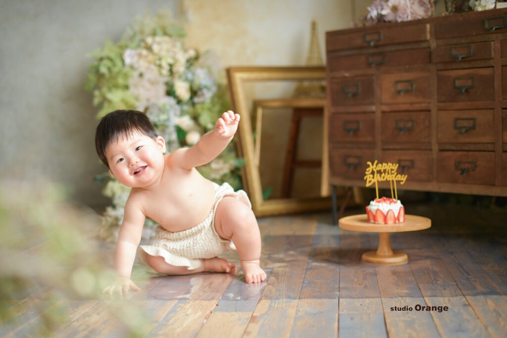 1歳男の子がスマッシュケーキの横ではーいと大きく手を挙げている瞬間
