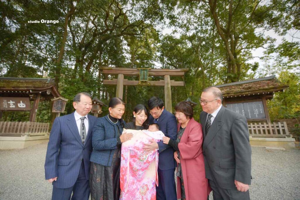 三輪神社で鳥居を背景にお宮参りの家族撮影
